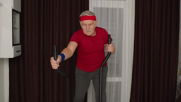 Active Healthy Senior Old Mature Man in Sportswear Using Orbitrek Training Cardio Workout at Home