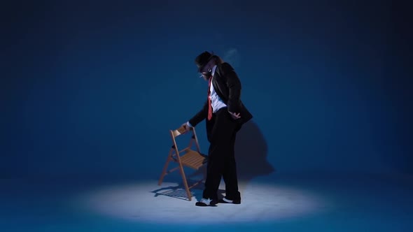 Elegant Man in a Black Hat Is Dancing an Erotic Dance. Spotlight on a Blue Background. Close Up