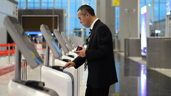Business man at the airport check in ticket at kiosk terminal
