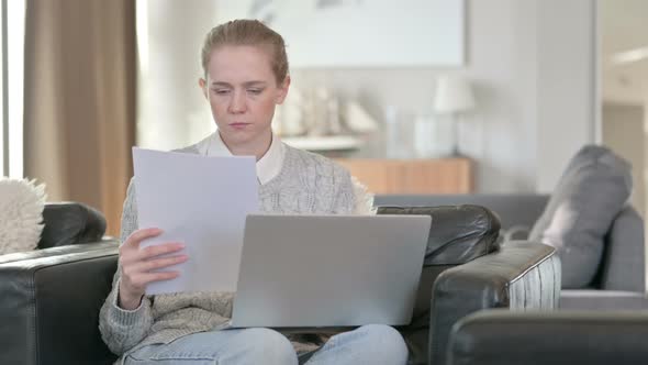 Young Woman Working on Laptop with Documents at Home 