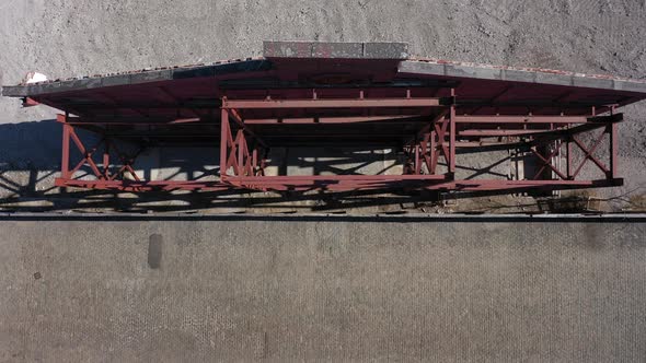 A top down view of an old building's red facade, supported by red steel beams. The camera boom down