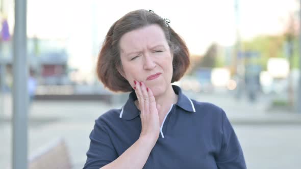 Outdoor Portrait of Old Woman with Toothache