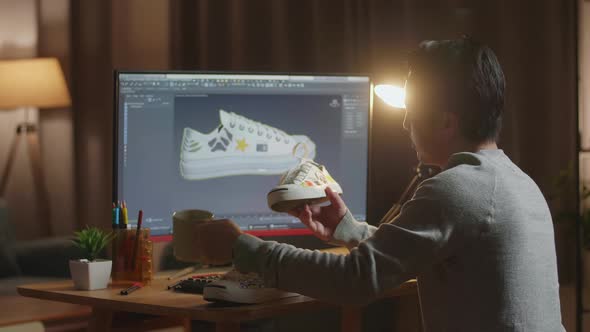 Asian Male Footwear Designer Drinking Coffee While Looking At Sneaker And Designing Shoe