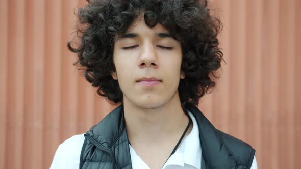 Closeup of Cute Teenage Boy Standing Outdoors with Eyes Closed Enjoying Peace and Solitude