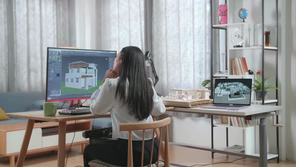Asian Woman Engineer Thinking While Designing House On A Desktop At Home. Cyber Games House Design