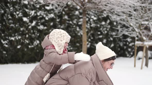 Mother Have Fun with Daughter in Winter Forest Playing with Snow