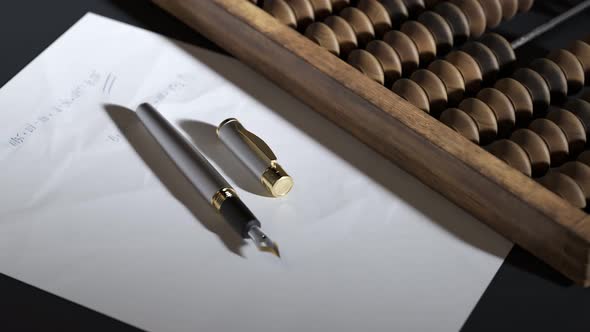 Vintage wooden abacus with fountain pen and paper with written calculations.