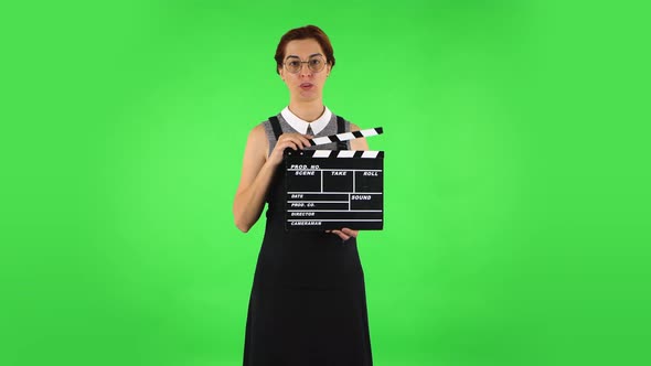 Funny Girl in Round Glasses Is Holding a Movie in Her Hands. Green Screen