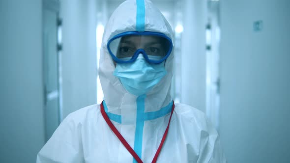 Clinic Worker in Protective Suit Looks at Camera.