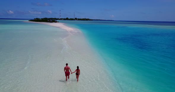 Young lady and man on romantic honeymoon live the dream on beach on sunny white sandy 4K background