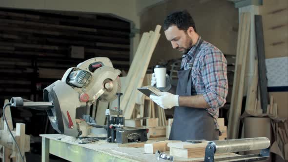 Man with Protection Gloves Using an Electric Saw To Cut a Plank