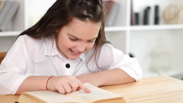 A little girl reads a book in the library