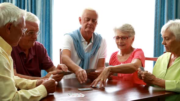 Senior friends playing cards in living room