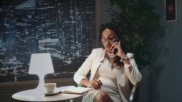 African American Business Woman in Eyeglasses Speaking By Smartphone with Something