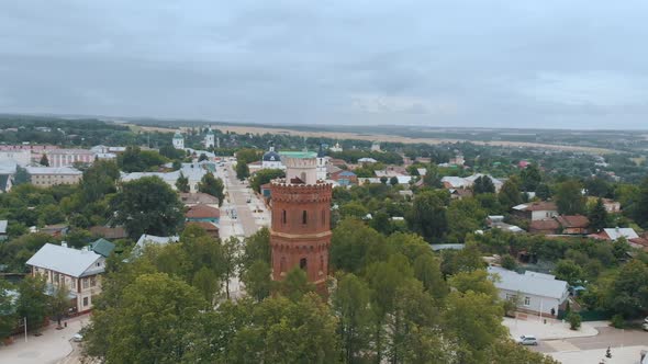 High Water Tower with Terracotta Bricks Among City Buildings