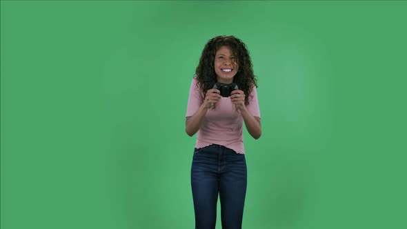 Portrait of Beautiful African American Young Woman Is Looking at Camera and Playing a Video Game