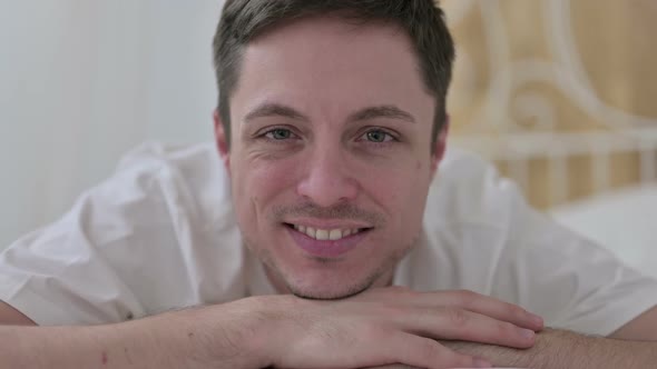 Close Up of Young Man Smiling at Camera in Bed