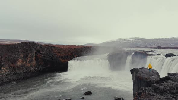 Woman climbing rock to admire waterfall