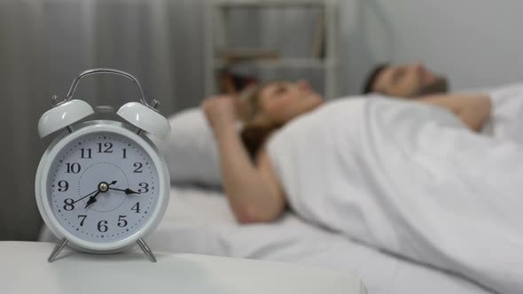 Happy Couple Waking Up With Alarm Clock in Morning and Kissing in Bed, Family