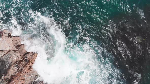 Aerial shot of ocean waves swirling around rocks with sea at Kauai, Hawaii, USA