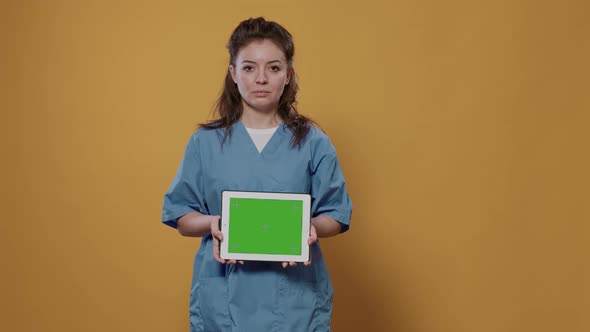 Portrait of Woman Doctor Holding Tablet Computer with Green Screen Wearing Hospital Uniform for