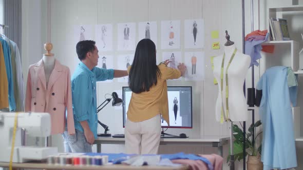 Asian Male And Female Designers Helping Each Other Putting The Picture On The Wall Before Discussing