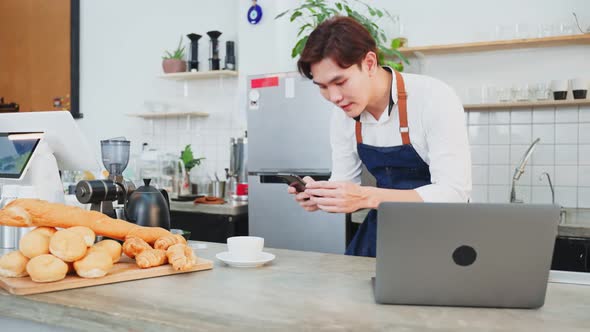 Young barista man use laptop computer enjoy post advertising picture on online social network.