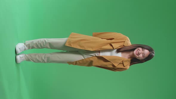 Full Body Of Young Asian Woman Warmly Smiling On Green Screen Background In The Studio
