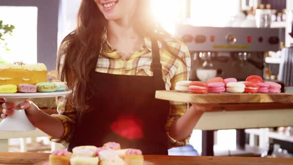 Portrait of waitress standing at counter with desserts