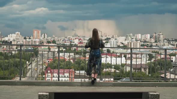 Stylish Woman Looks at Large Modern City From Viewing Deck