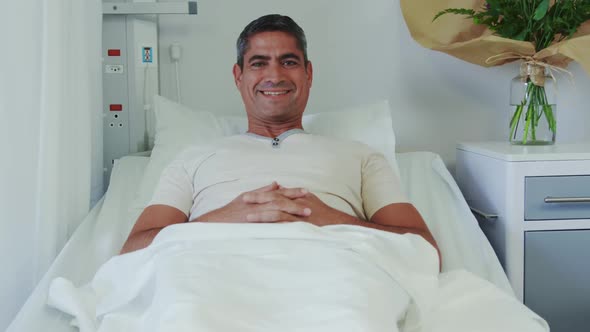 Front view of Caucasian male patient relaxing on hospital bed in hospital ward 