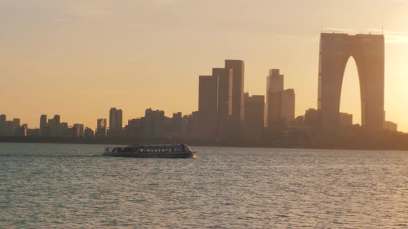 Slow motion view of pleasure boat sails on the lake on sunset, cityscape on the background