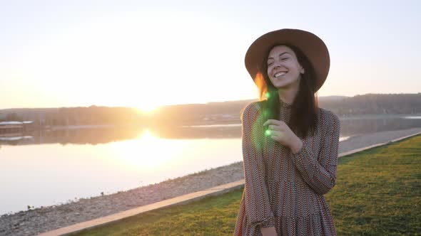 Adorable Young Girl with Hat Smiling Posing at Camera Near the Lake