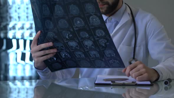 Oncologist Examining Brain X-Ray and Writing Diagnosis in Medical Form, Health