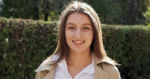 Portrait of Young Attractive Female Who Smiling and Looking at the Camera on Green Historical Urban