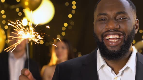 Cheerful African-American Man Holding Bengal Light at Party Celebrating New Year