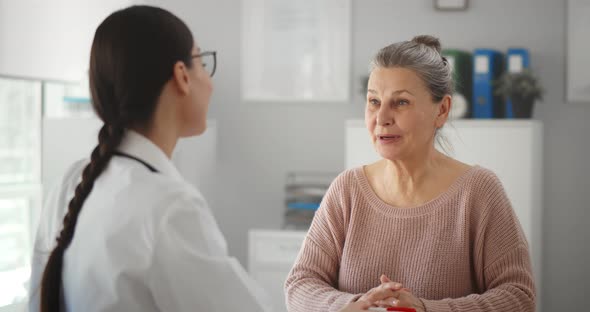 Specialist Giving Consultation to Aged Woman Sitting at Desk in His Office