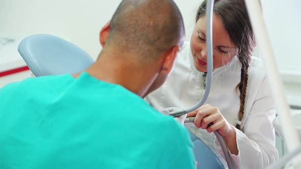 Girl sitting in the dental chair giving high five to dentist and assistant