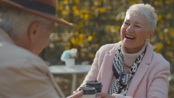 Happy Senior Couple Enjoying Takeaway and Talking At Outdoor Cafe