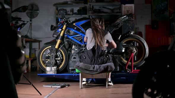 Young woman in the service repairs a motorcycle. Young mechanic working on moto
