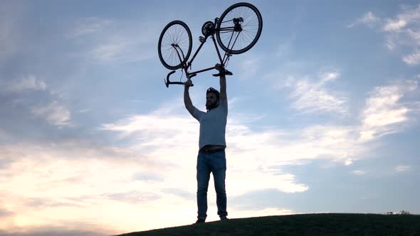 Young Man Lifting Bicycle Above Head