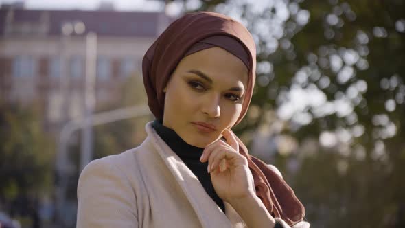 A Young Beautiful Muslim Woman Thinks About Something and Nods in a Park in an Urban Area  Closeup