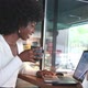 Happy African American Woman Sitting in Cafe with Coffee Working on Laptop and Phone Freelance - VideoHive Item for Sale