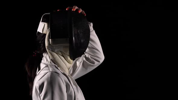 Side View of Young Woman Fencer Puts Protective Sports Mask Helmet