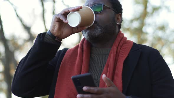 Smiling African man drinking coffee in park