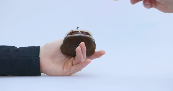 Male Hand Puts a Cryptocoin Bitcoin or BTC in a Small Brown Wallet Depicting Earning or Paying with