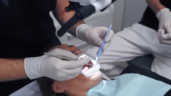 Close-up woman's face with opened mouth at dentist. Doctor hands in gloves examines patient's teeth