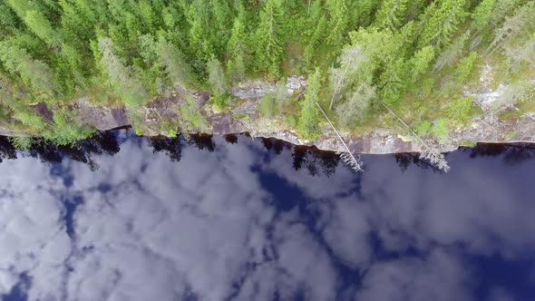 Surreal drone shot of the shoreline of a forest lake in boreal wilderness. Pristine mirror surface l