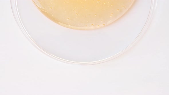 Yellow Transparent Cosmetic Gel Cream With Molecule Bubbles Flowing On The Plain White Surface