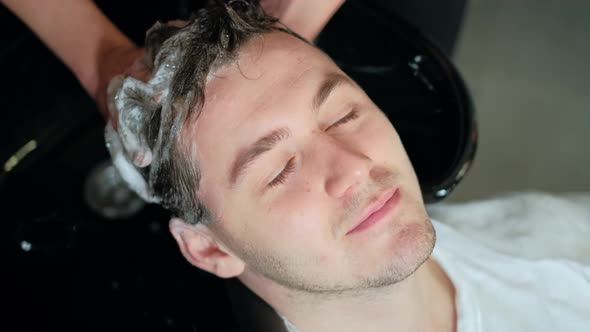 Close-up. Stylist Washes the Hair of the Man in the Beauty Salon or Barbershop. Hairdresser Man